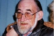 A man with glasses is cropped from an image