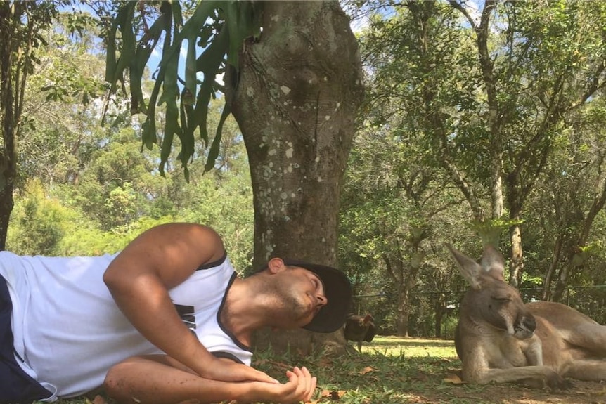 a man lies down next to a kangaroo in the bush