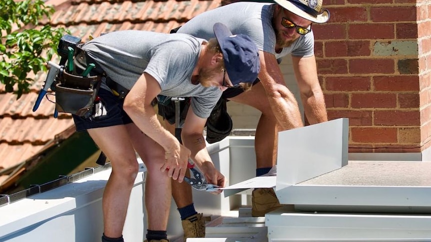 Two tradies at work on the roof of a house under construction