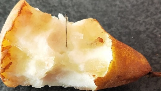 A needle lodged in a pear.