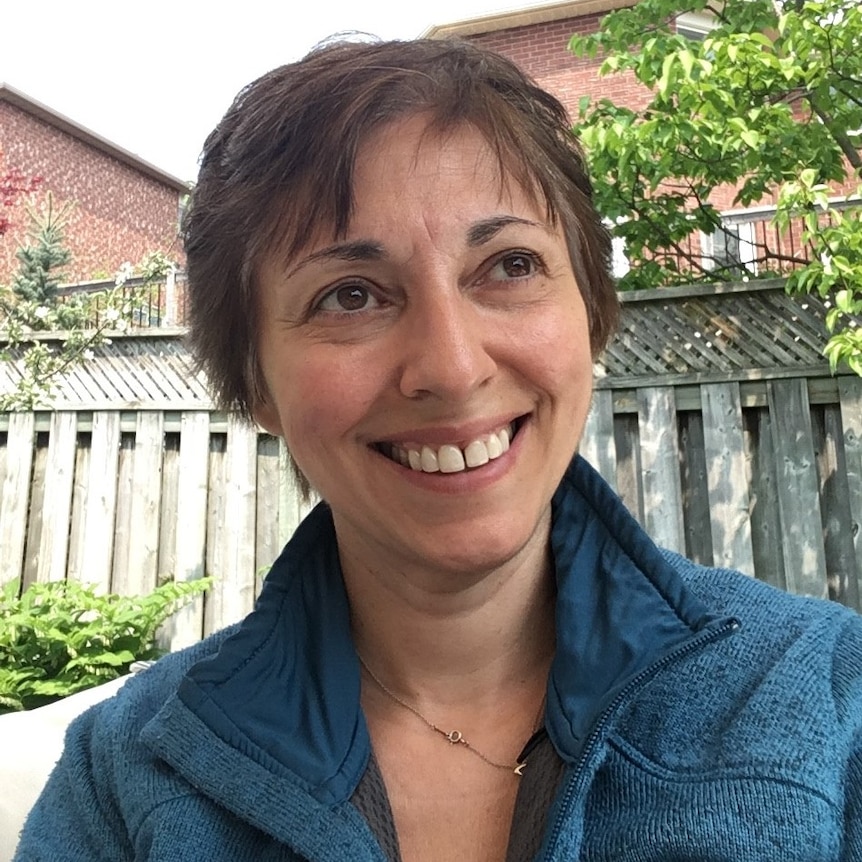 A woman with short hair smiles broadly while looking at the camera.