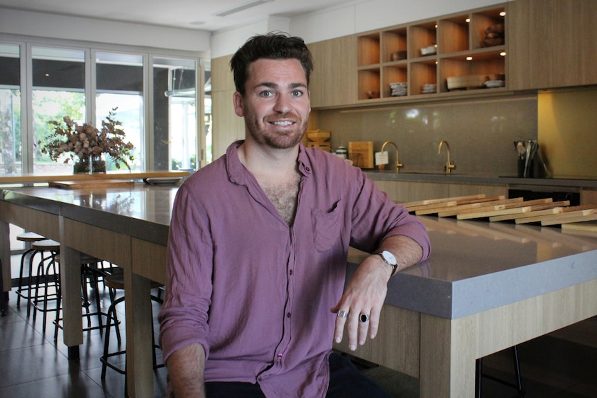 A man sits next to a large stone kitchen island.