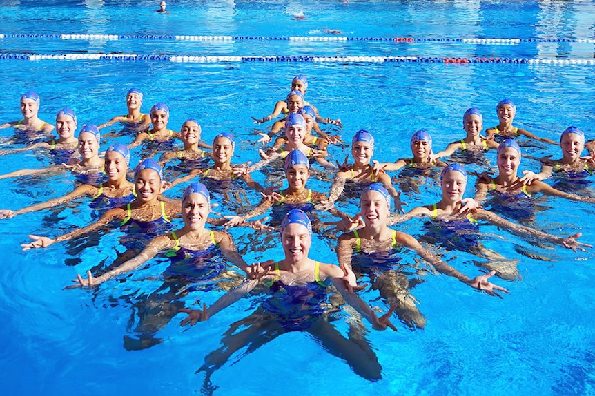 A group of female synchronised swimmers in a pool.