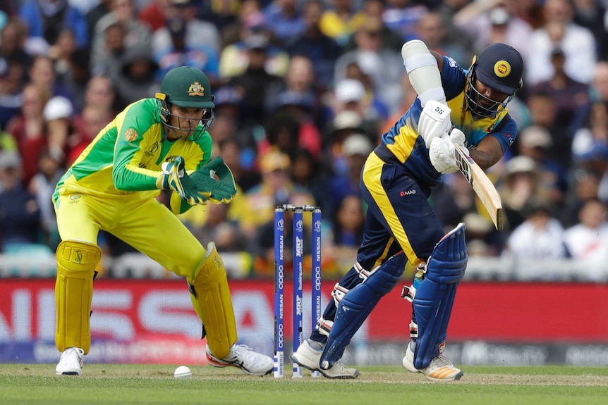 Kusal Perera hits the ball into the on side, while Alex Carey looks on from behind the stumps with gloves ready.