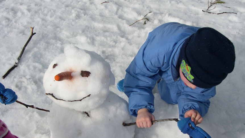 Children building a snowman with carrot for nose at Mount Selwyn snowfields, NSW.
