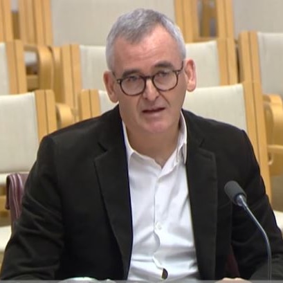 Man in suit speaks inside senate committee room