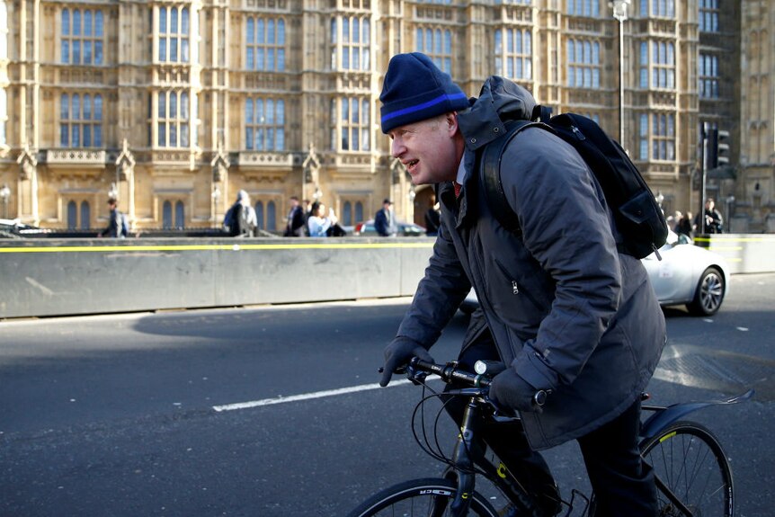 Boris Johnson riding his bike outside the Houses of Parliament in London