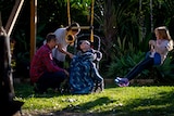 A mother and father with a child in a wheelchair, and another child on a swing.