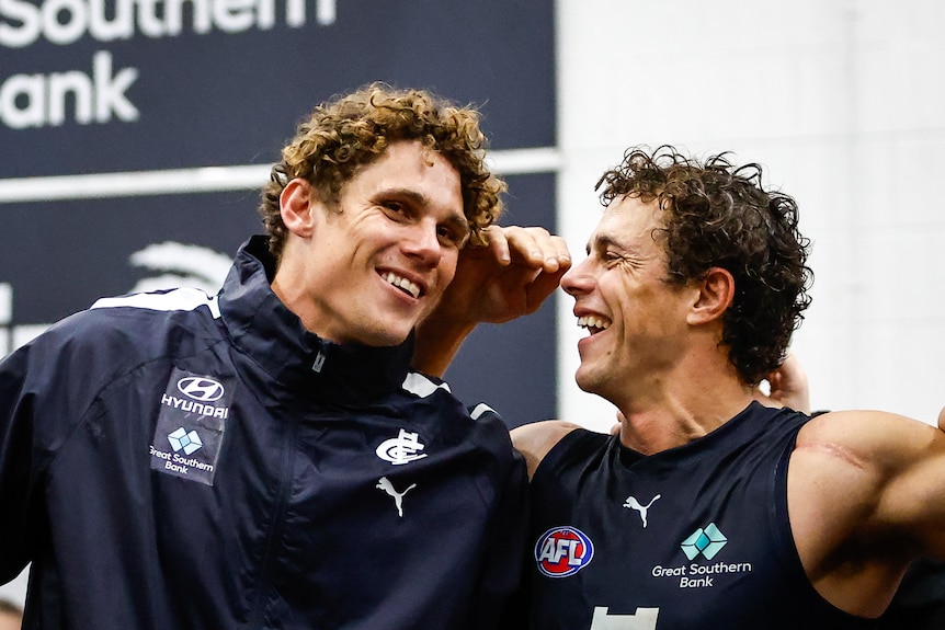 Charlie Curnow and Ed Curnow smile together while arm in arm in the rooms after a win