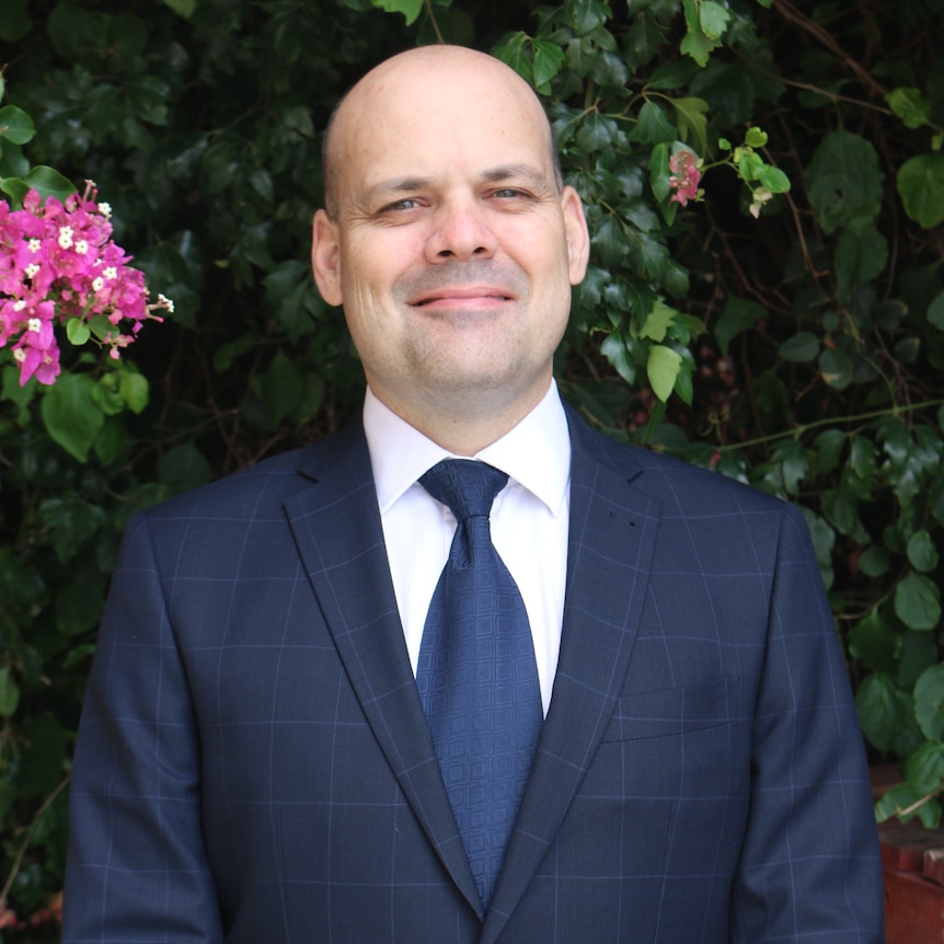 A smiling man in a dark suit.