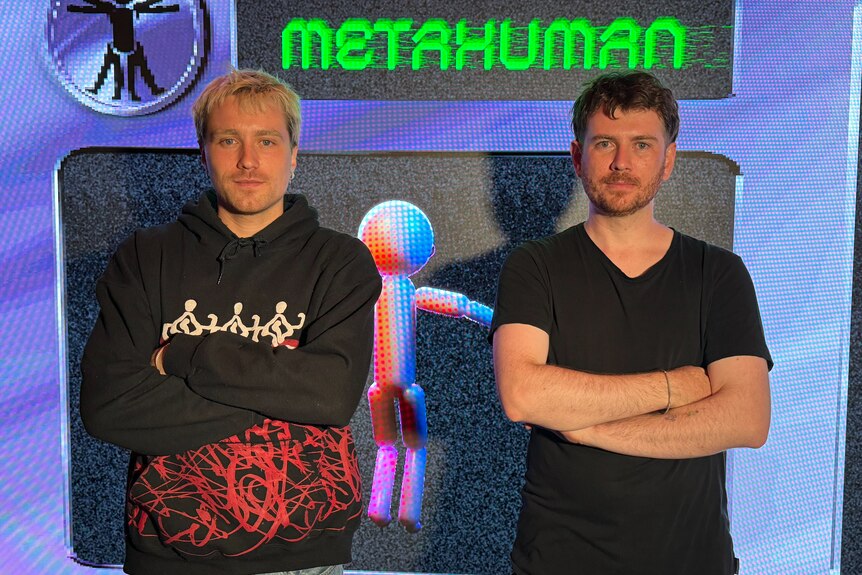 Two men standing with their arms crossed in front of a digital screen that says metahuman