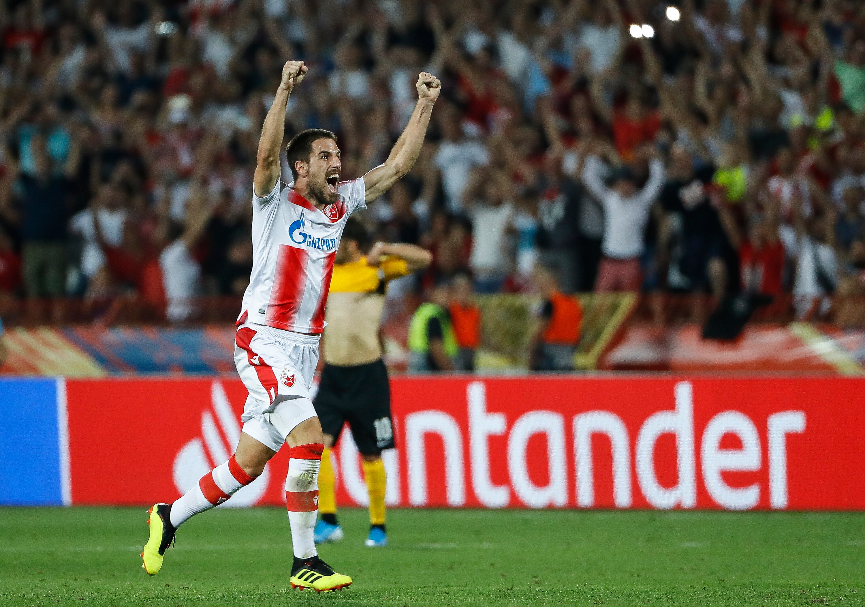A soccer player wearing white and red stripes celebrates after winning a game
