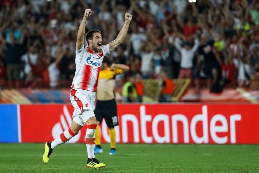 A soccer player wearing white and red stripes celebrates after winning a game