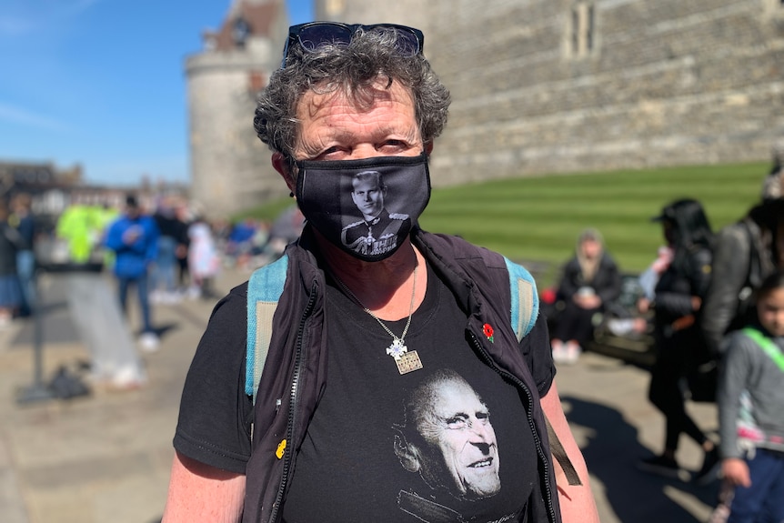 a woman wearing a face mask and shirt featuring the prince philip's image