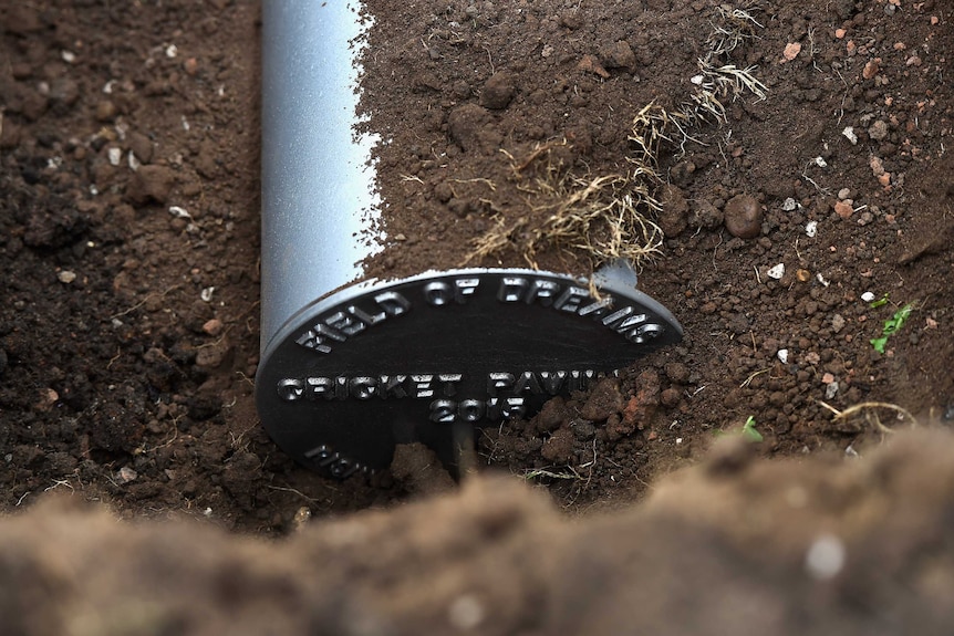 A silver time capsule poking out from the dirt.