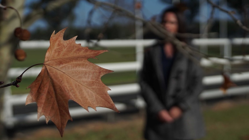 A woman stands near a tree