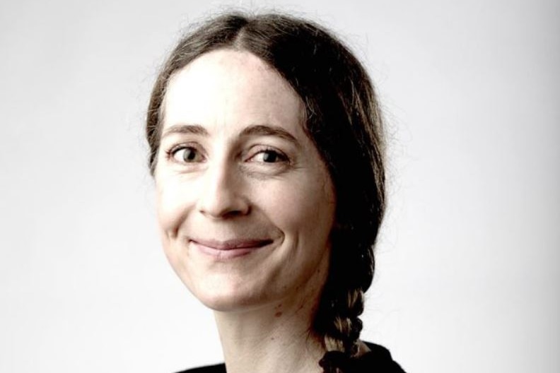 A black and white head shot of Nicola Henry smiling at the camera