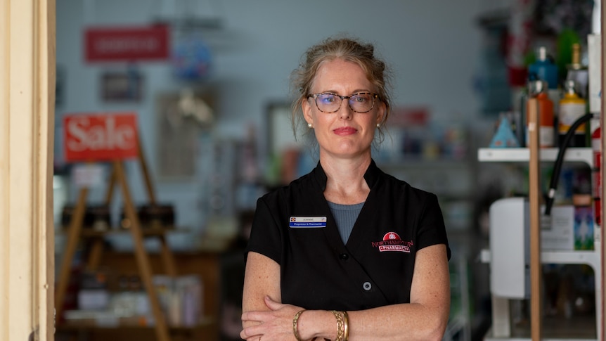 Woman in a black shirt standing in the doorway of a pharmacy. 