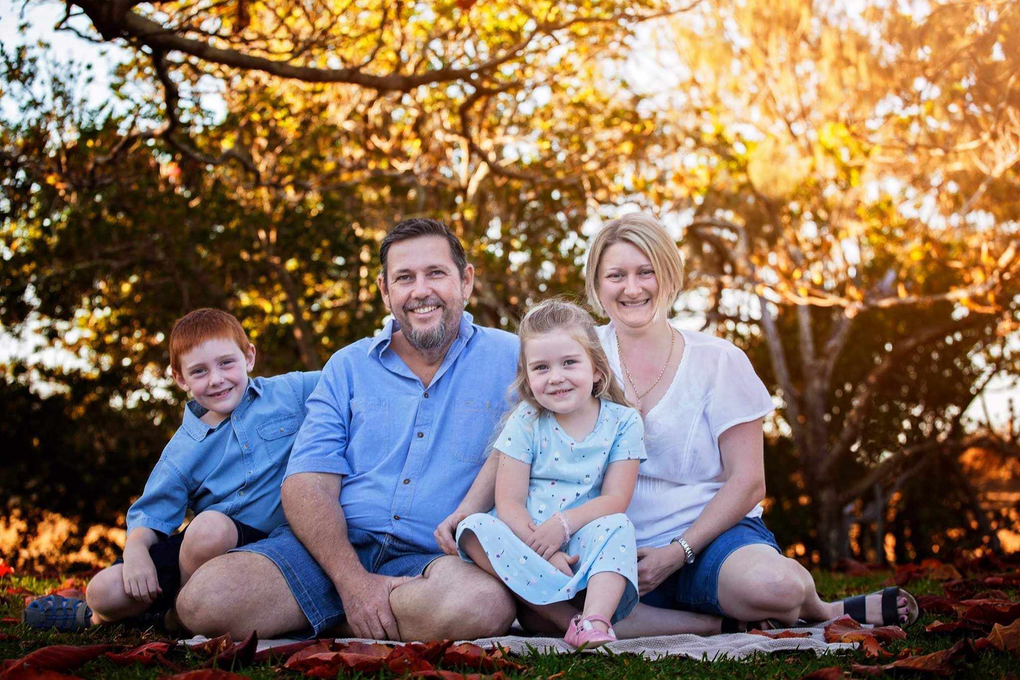 A family of four smile at the camera. 