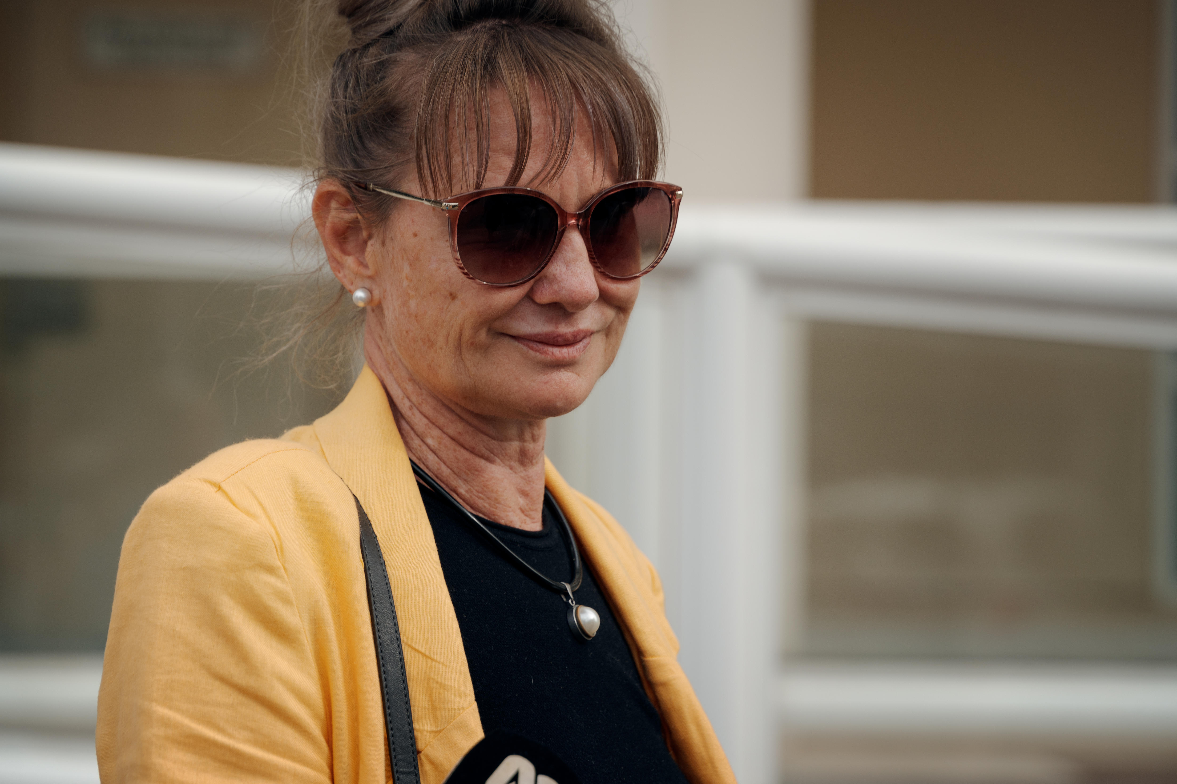 A woman in a yellow jacket and sunglasses