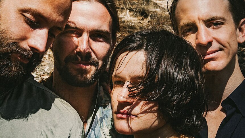 Four members of band Big Thief stand very close to each other