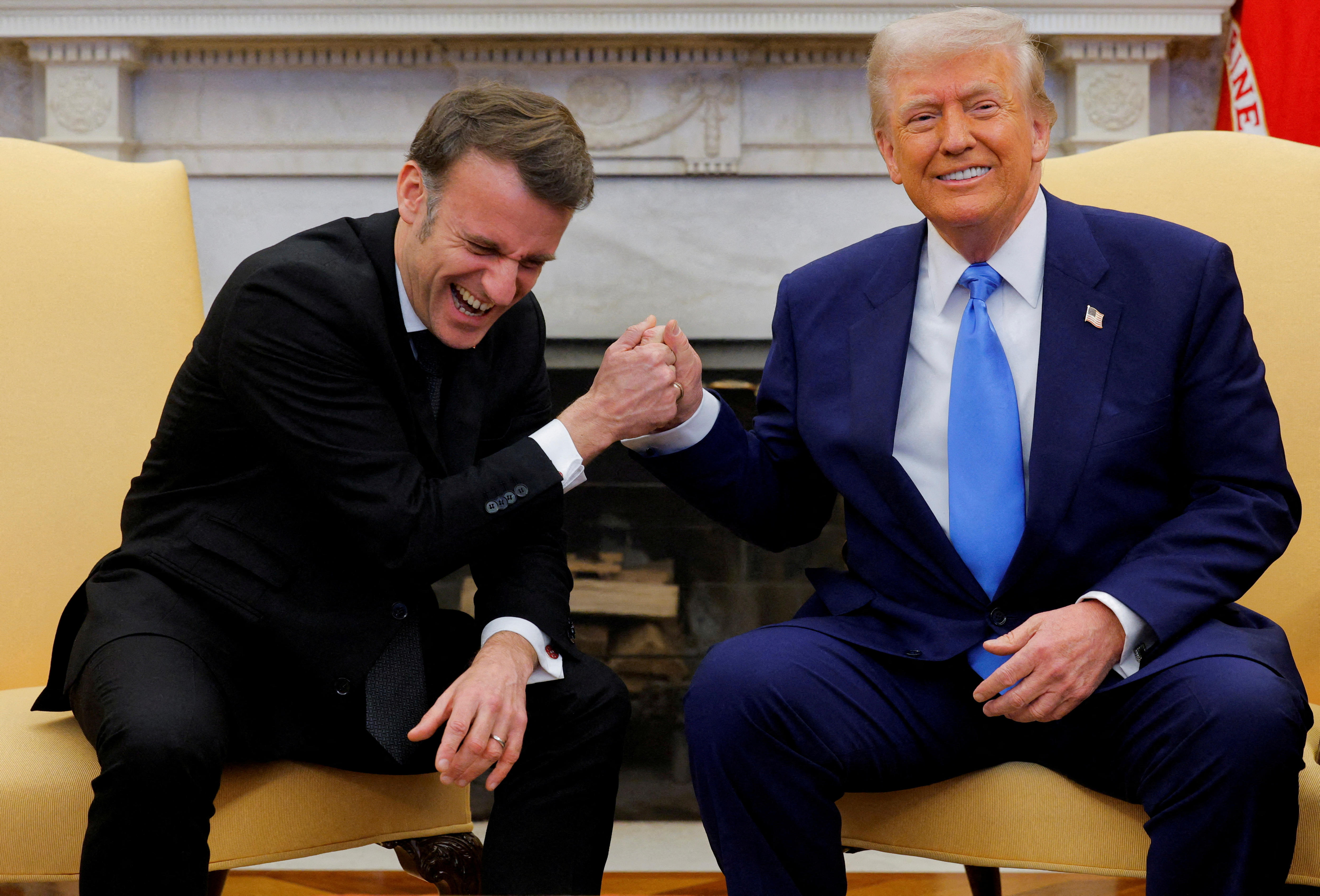 Two men in suits laughing and gripping hands 
