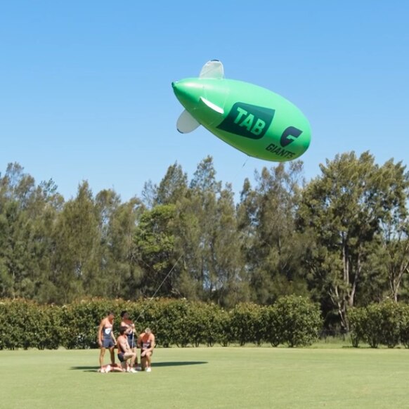 Giants players and green TAB x GWS blimp