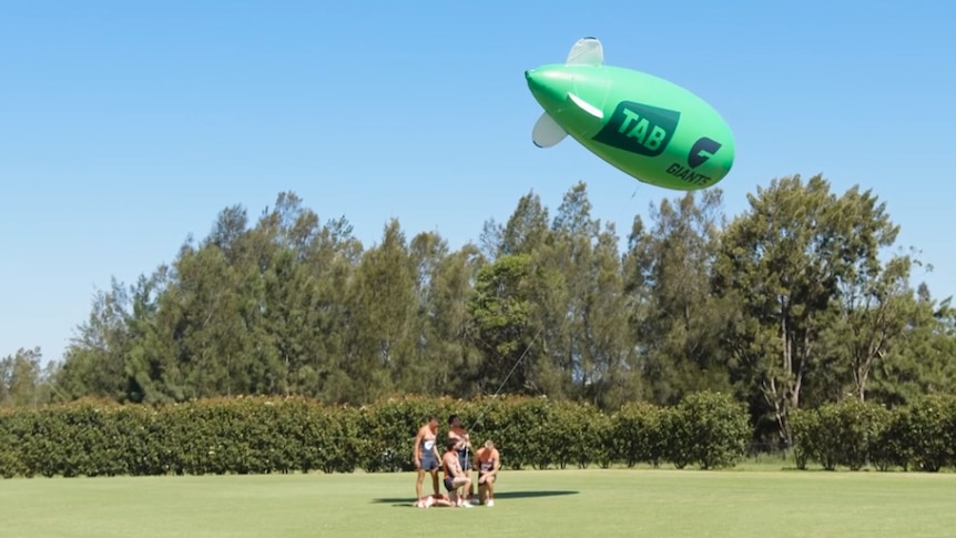 Giants players and green TAB x GWS blimp