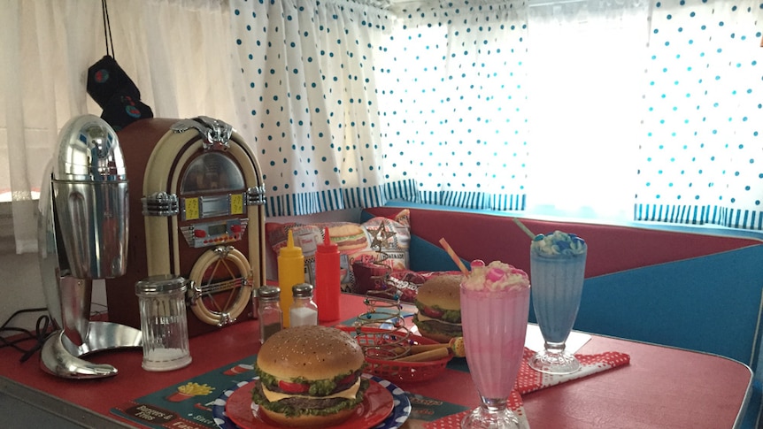 Dukebox, fake hamburger and milkshakes from the 1950s era on an old caravan table.