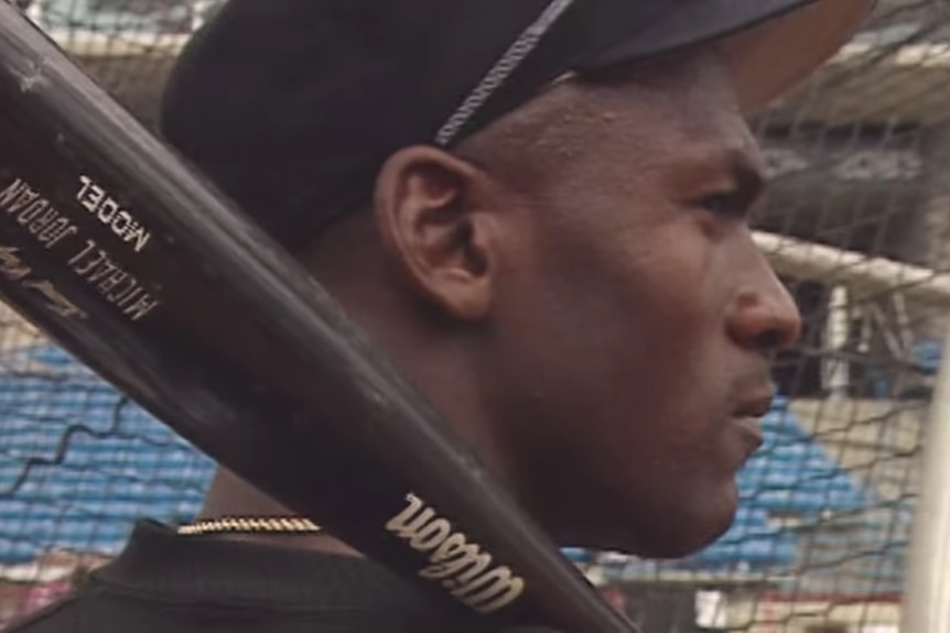 Michael Jordan holds a baseball bat over his shoulder.