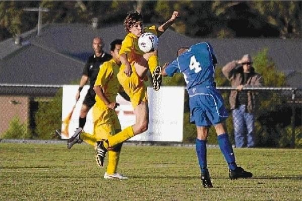 Two male soccer players, one wearing yellow and another wearing blue, compete for the ball
