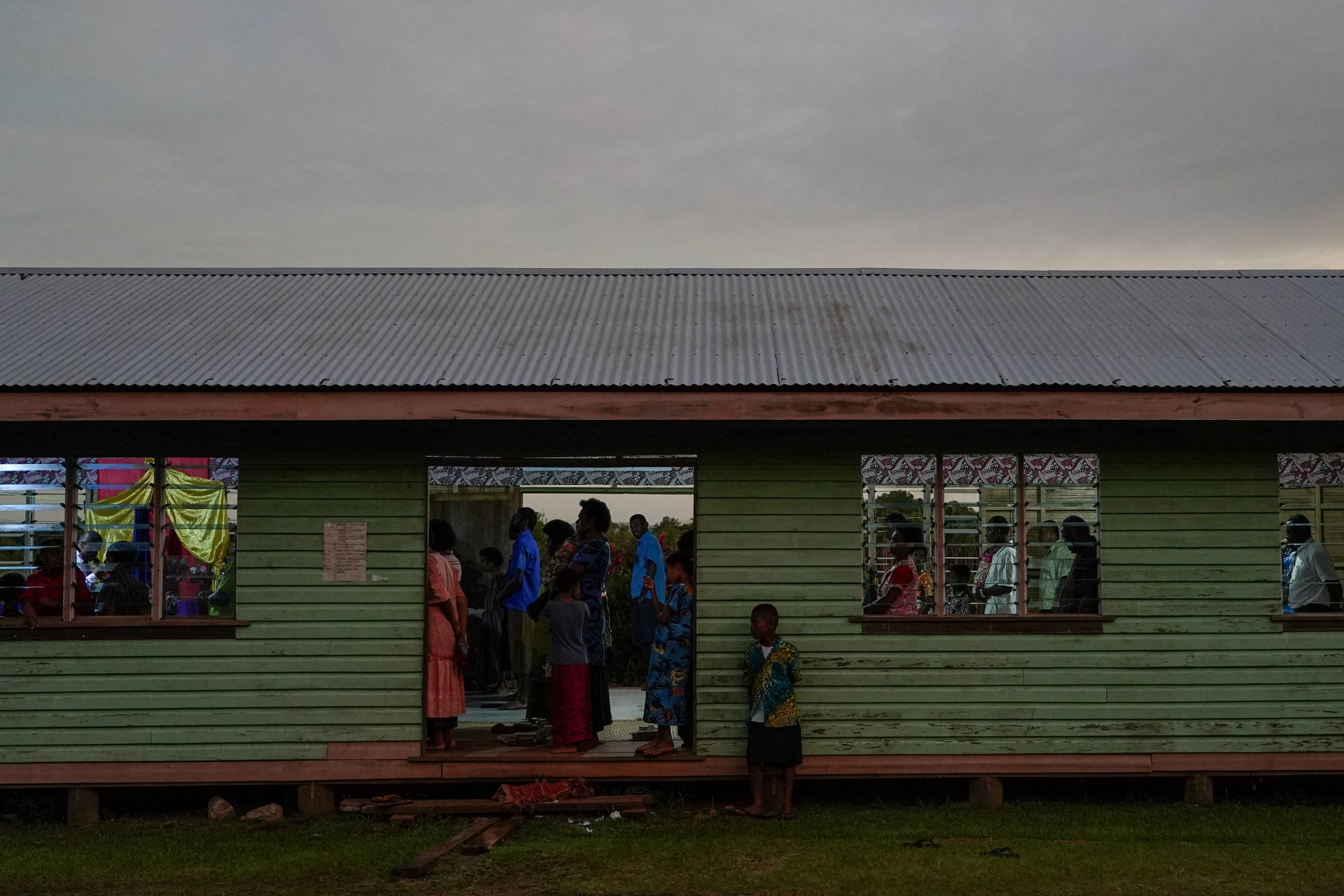 People gathered for a Sunday church service. Their village moved to the mainland and there are no floodwaters in sight