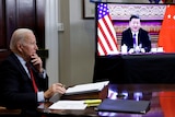 US President Joe Biden sitting down with a monitor on to the right of the image showing Chinese President Xi Jinping