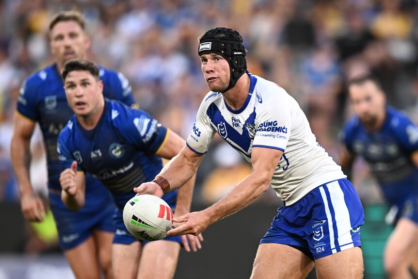 NRL player Matt Burton prepares to pass the ball with both hands during a match against the Eels