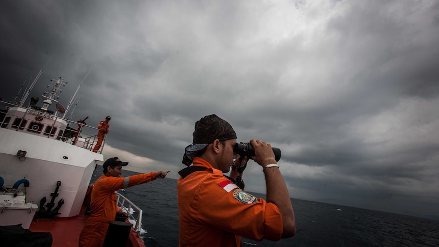 An Indonesian search and rescue member looks through binoculars during a search in the Andaman Sea