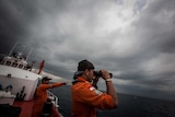 An Indonesian search and rescue member looks through binoculars during a search in the Andaman Sea