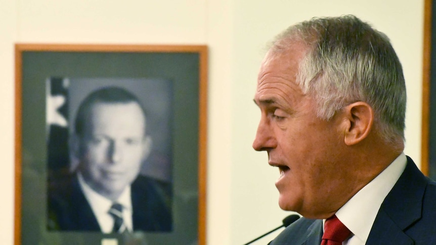 Malcolm Turnbull speaks in front of photo of Tony Abbott