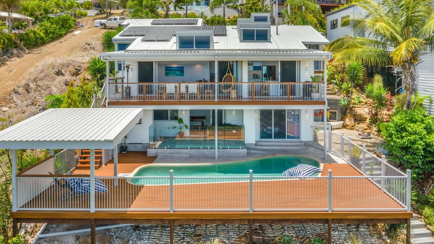 A large, luxury home on a hill with a pool