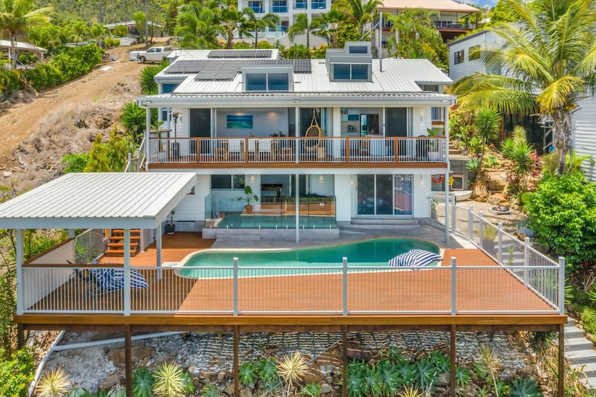 A large, luxury home on a hill with a pool