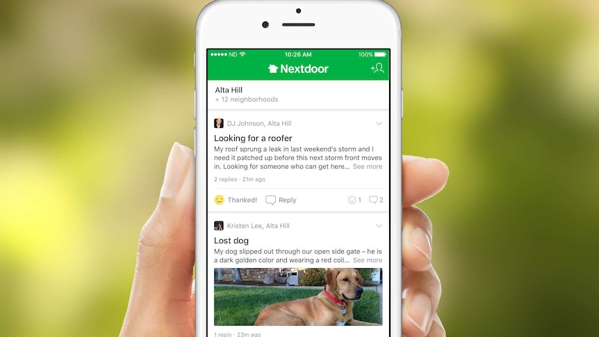 A hand holding a smartphone with the Nextdoor app open.