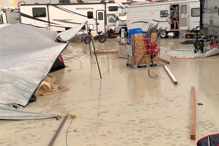 A mud covered campsite with broken tents strewn