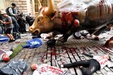 Climate change activists lay on the ground covered in fake blood at the feet of the Wall Street Bull statue.