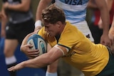 A man wearing yellow dives while holding the ball and being held by a man in a white and blue shirt