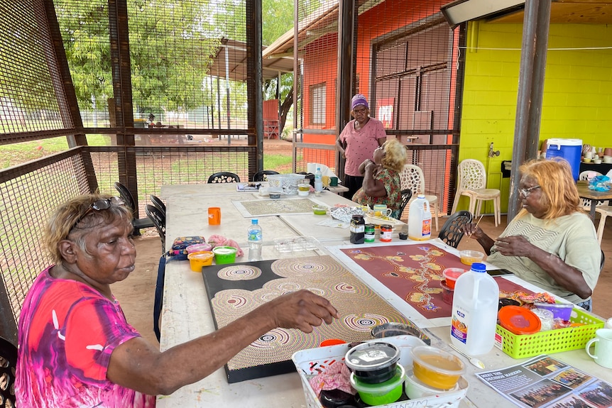 Four Aboriginal women sit at a table painting