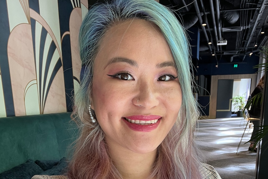 A woman with green hair smiling at the camera.