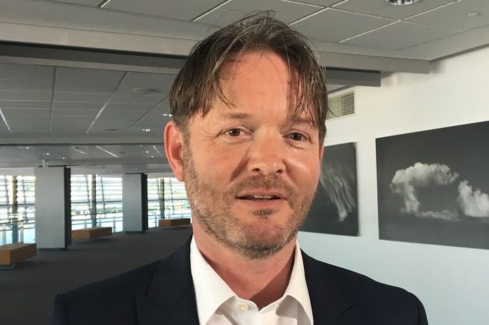 Martin Wilkes wears a suit and is pictured in a large indoor room