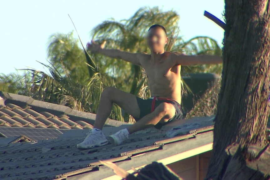 A man sitting on a roof with his arms open wide
