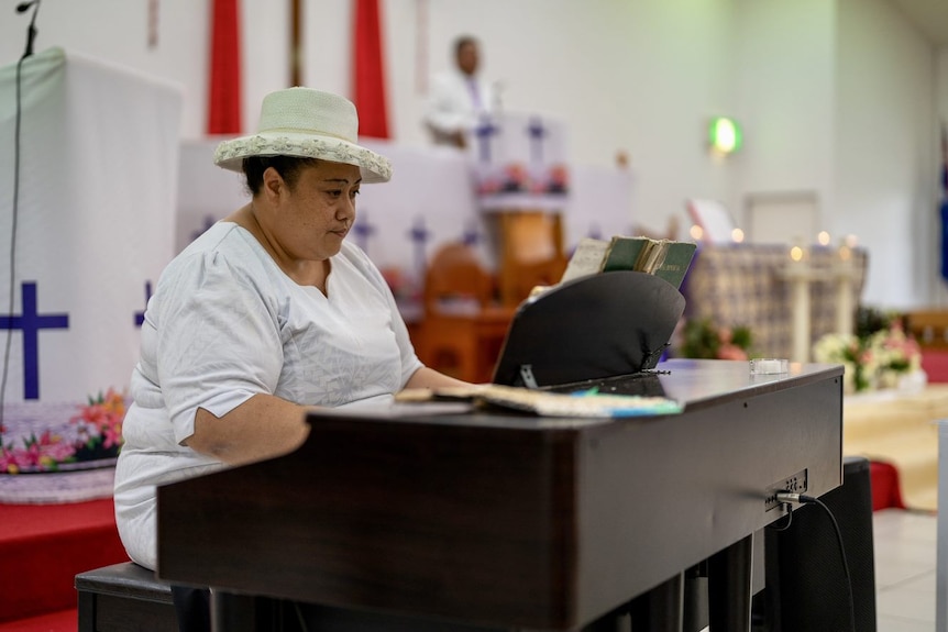 A woman sits at the piano inside a church in Brisbane. 