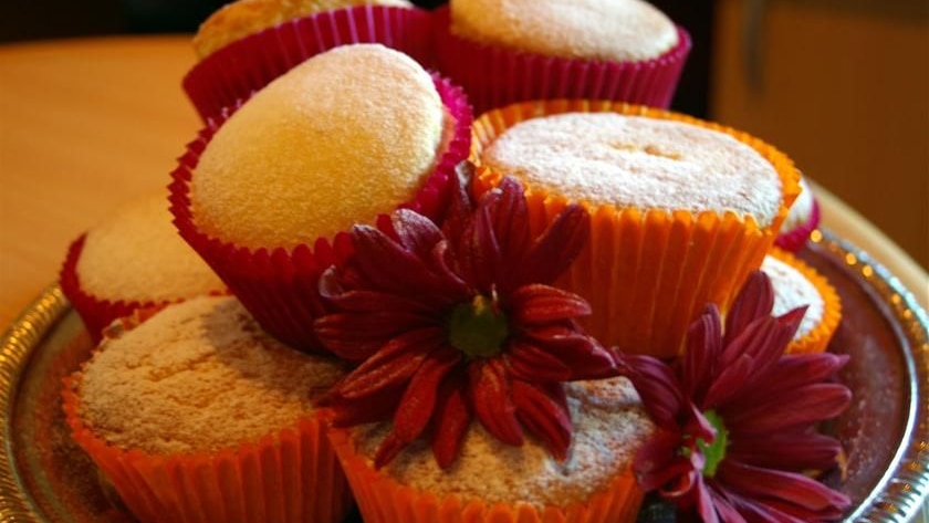 A pile of cupcakes, decorated with fresh flowers.