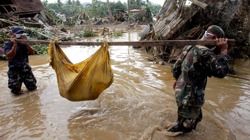 Soldiers carry the body of a child drowned by flash floods caused by Typhoon Washi.